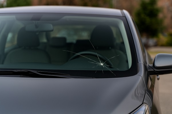 Dark gray car with a cracked windshield showing a star-shaped fracture slightly to the right of center.