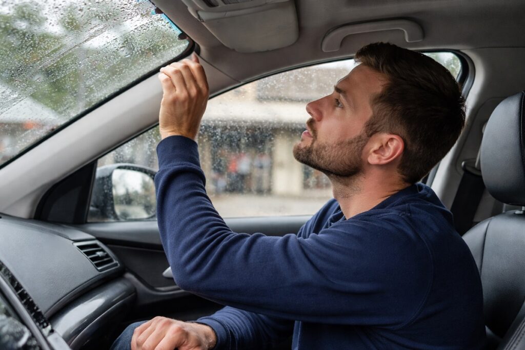 Driver checking windshield seal for leaks after new auto glass installation