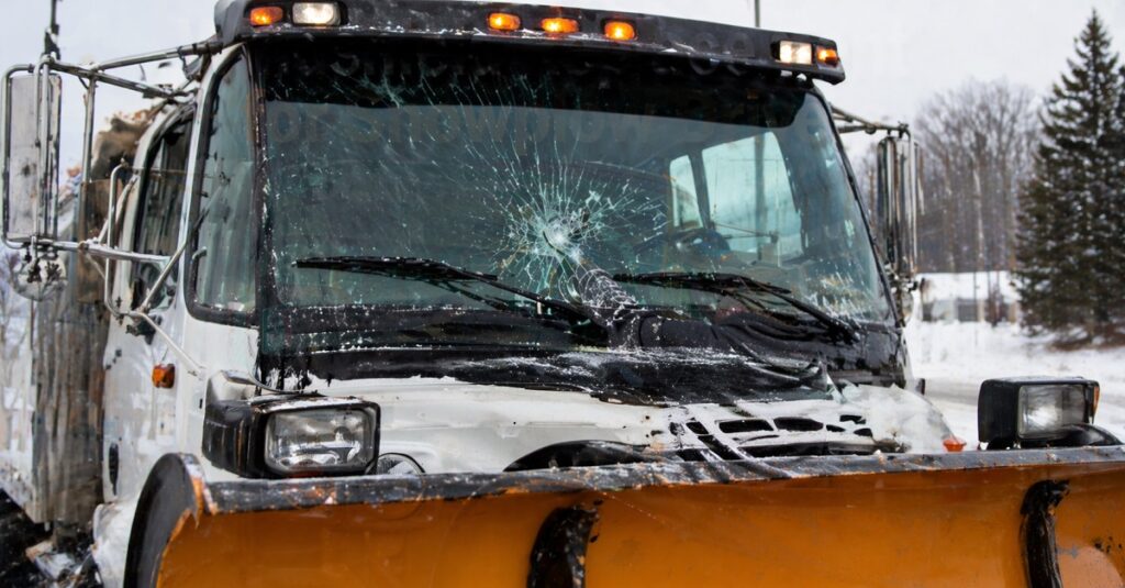 Cracked windshield on snowplow truck from ice and road debris impact